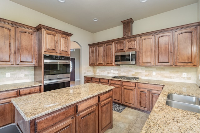 kitchen with decorative backsplash, sink, light tile patterned floors, appliances with stainless steel finishes, and light stone counters