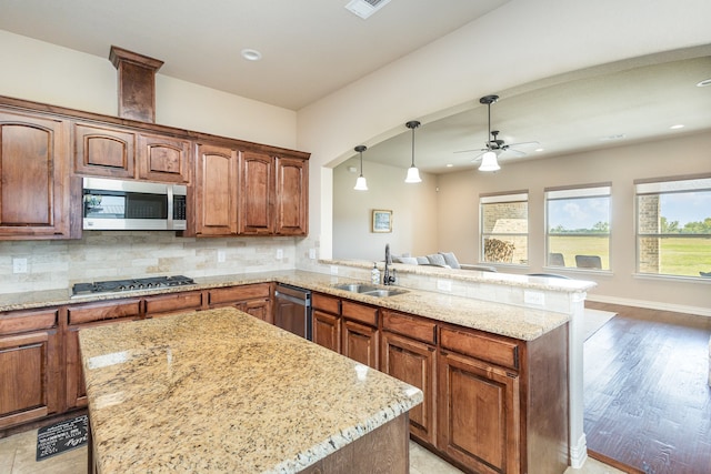 kitchen with kitchen peninsula, stainless steel appliances, backsplash, sink, and light hardwood / wood-style floors