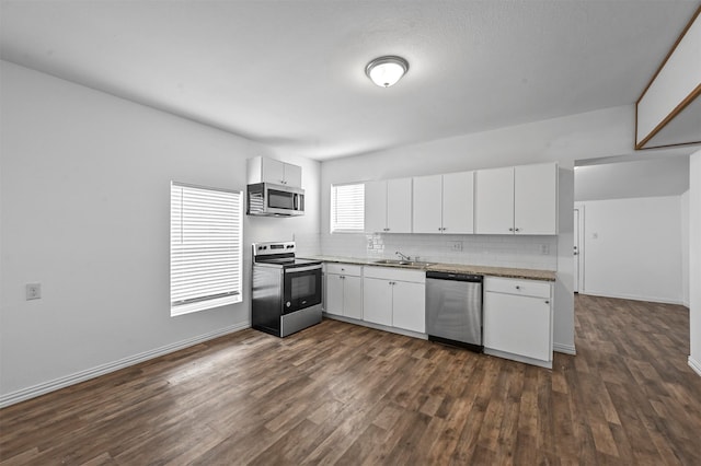 kitchen featuring dark wood-type flooring, appliances with stainless steel finishes, decorative backsplash, and white cabinets