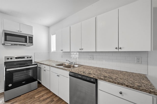 kitchen with sink, stainless steel appliances, dark stone counters, white cabinets, and dark hardwood / wood-style floors