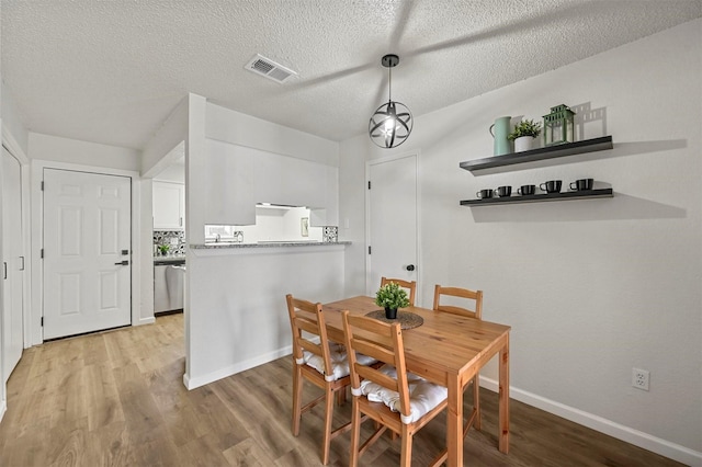 dining area featuring light hardwood / wood-style floors and a textured ceiling