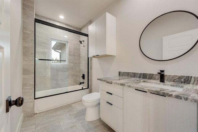 full bathroom featuring vanity, combined bath / shower with glass door, and toilet