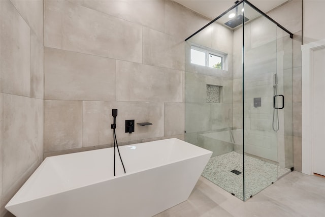 bathroom featuring tile walls and separate shower and tub