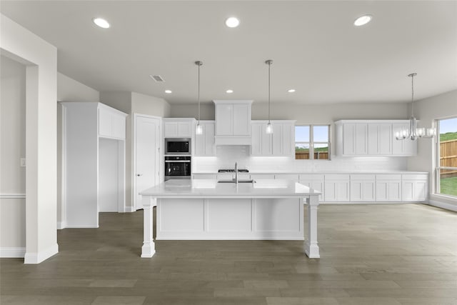 kitchen featuring a center island with sink, hardwood / wood-style floors, white cabinets, and stainless steel appliances