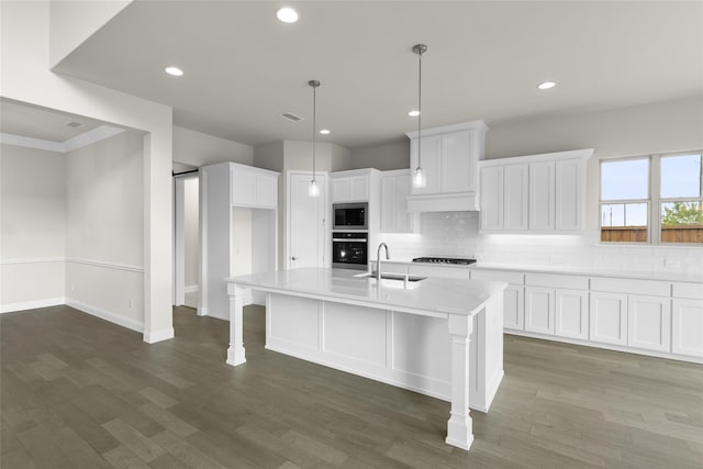 kitchen with a kitchen island with sink, ornamental molding, sink, white cabinets, and appliances with stainless steel finishes