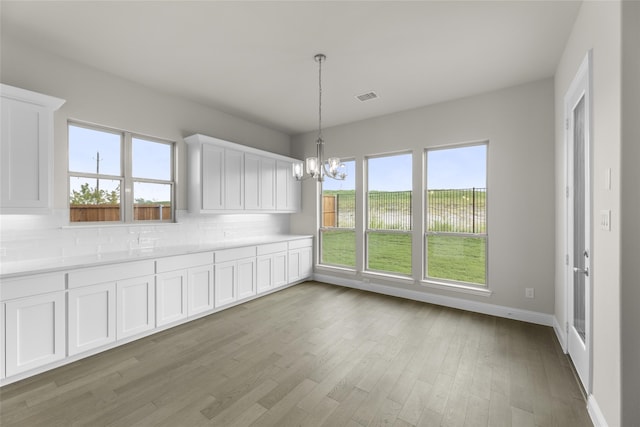 unfurnished dining area featuring light hardwood / wood-style floors and an inviting chandelier