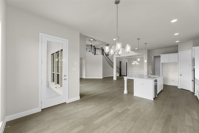 kitchen featuring white cabinetry, light hardwood / wood-style floors, an island with sink, and hanging light fixtures