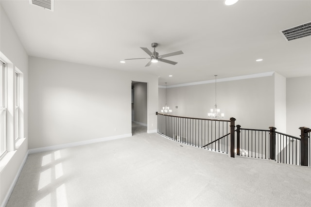 empty room with ornamental molding, light carpet, and ceiling fan with notable chandelier