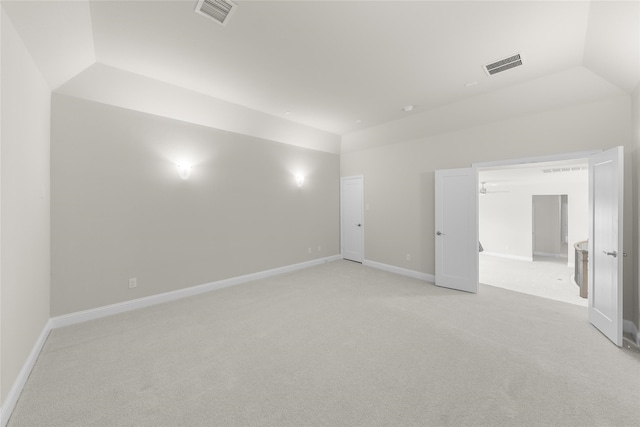 spare room featuring lofted ceiling and light colored carpet