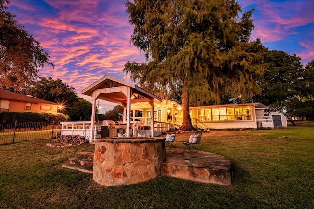 back house at dusk with a patio, a bar, a storage shed, and a yard