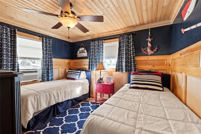 bedroom featuring ceiling fan, cooling unit, wooden ceiling, ornamental molding, and wood walls