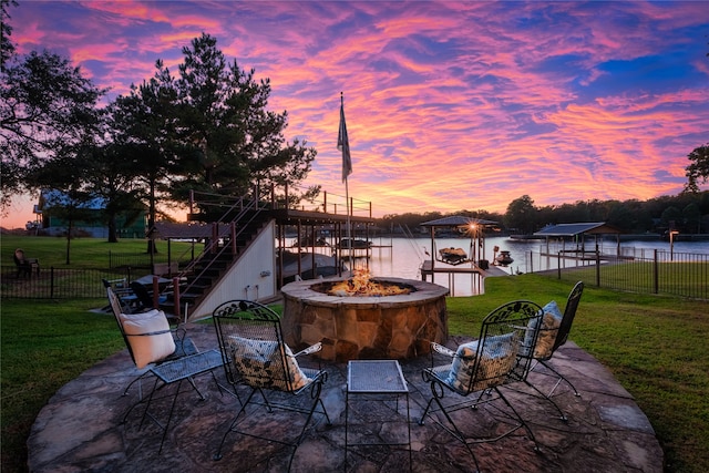 patio terrace at dusk with a yard, a water view, and a fire pit