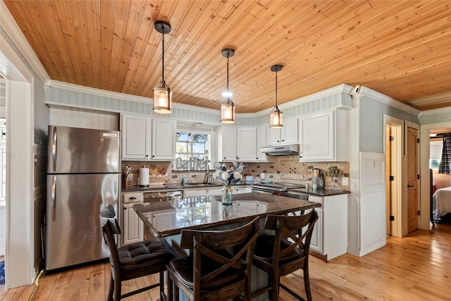 kitchen featuring appliances with stainless steel finishes, a kitchen island, white cabinetry, pendant lighting, and ornamental molding