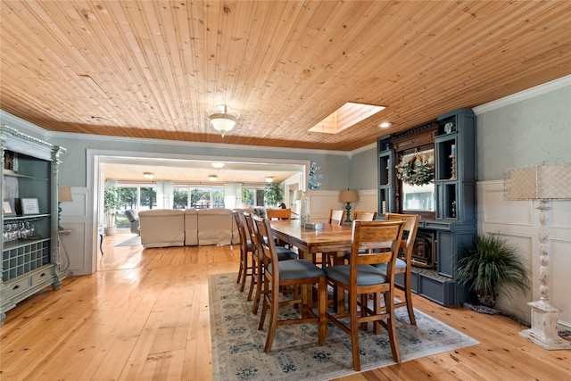 dining room featuring light hardwood / wood-style floors, ornamental molding, a skylight, and wood ceiling