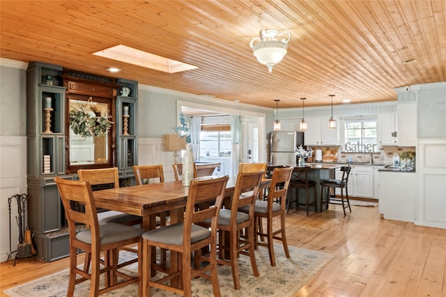 dining space featuring light hardwood / wood-style floors, a healthy amount of sunlight, wooden ceiling, and a skylight