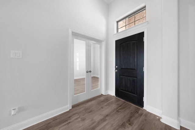 foyer entrance featuring dark wood-type flooring, french doors, and baseboards