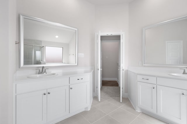 full bath with a sink, a shower with shower door, two vanities, and tile patterned floors