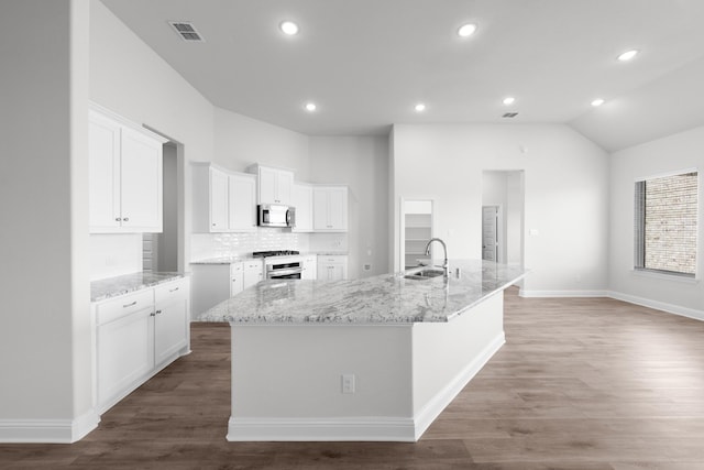 kitchen with stainless steel microwave, wood finished floors, visible vents, and a sink