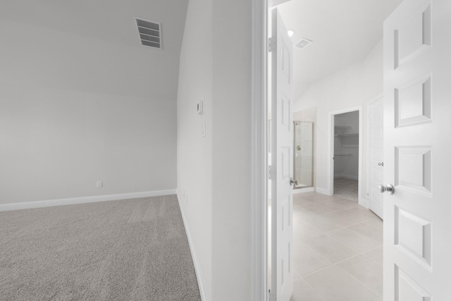 hallway featuring light carpet, visible vents, lofted ceiling, and baseboards