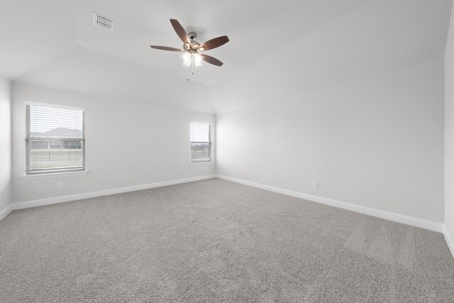 carpeted empty room with vaulted ceiling, baseboards, visible vents, and ceiling fan