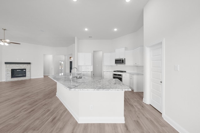 kitchen with a sink, stainless steel appliances, light wood-type flooring, and white cabinetry