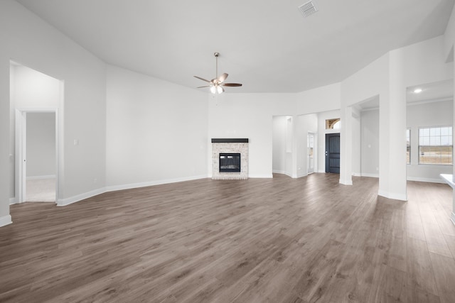 unfurnished living room featuring visible vents, a ceiling fan, wood finished floors, and a fireplace