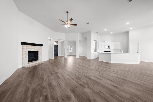 unfurnished living room featuring wood finished floors, baseboards, a fireplace, recessed lighting, and ceiling fan