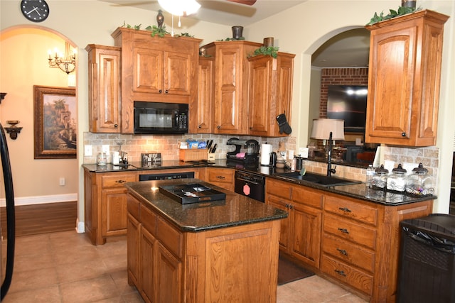 kitchen featuring sink, tasteful backsplash, dark stone counters, a kitchen island, and black appliances