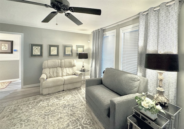 living room with ceiling fan, ornamental molding, a textured ceiling, and hardwood / wood-style floors