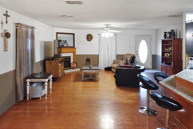 101 Scenic Dr, Dublin, TX 76446 - living room with wood finished floors, a ceiling fan, a wainscoted wall, and a glass covered fireplace