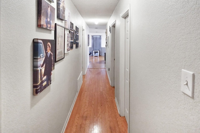 101 Scenic Dr, Dublin, TX 76446 - hall with light wood finished floors, a textured wall, and baseboards