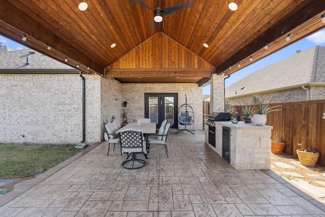 view of patio with area for grilling, fence, french doors, exterior kitchen, and outdoor dining area