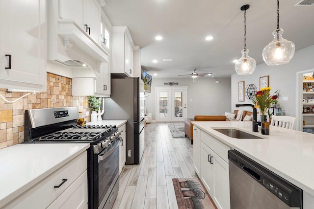 kitchen featuring stainless steel appliances, sink, hanging light fixtures, and white cabinets