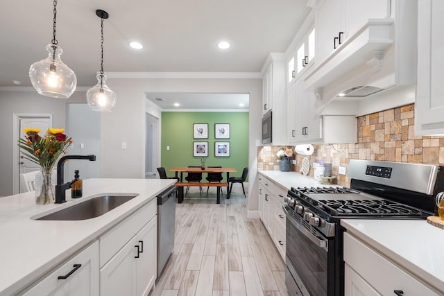 kitchen featuring appliances with stainless steel finishes, sink, white cabinets, and decorative light fixtures