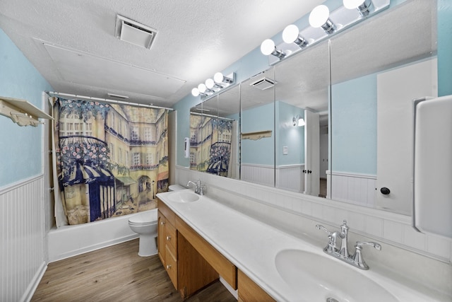 full bathroom with toilet, vanity, shower / bath combo with shower curtain, hardwood / wood-style flooring, and a textured ceiling