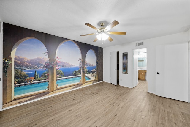 empty room with ceiling fan and light hardwood / wood-style flooring