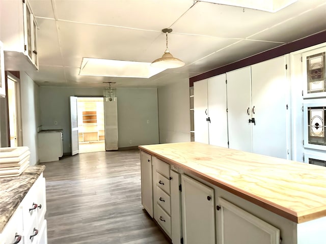 kitchen featuring white cabinets, butcher block counters, dark wood-type flooring, and hanging light fixtures