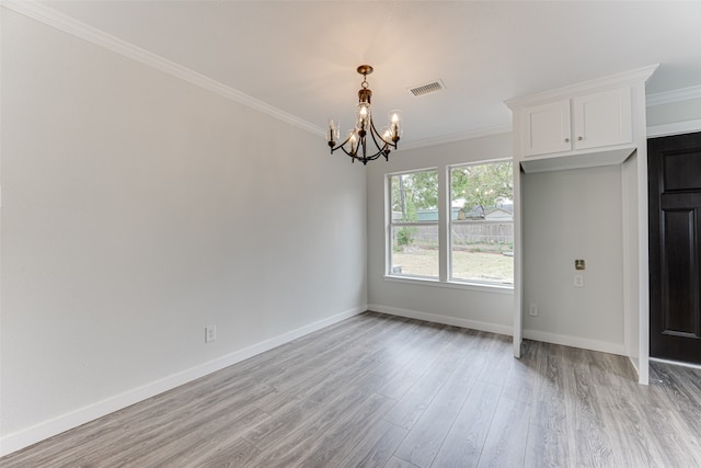 unfurnished room with crown molding, an inviting chandelier, and light wood-type flooring