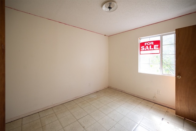 unfurnished room with a textured ceiling