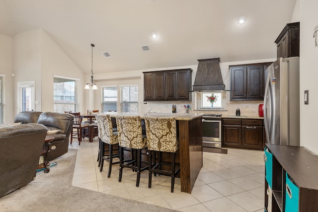 kitchen with appliances with stainless steel finishes, premium range hood, a kitchen island, and hanging light fixtures