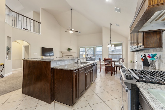 kitchen featuring a center island with sink, ceiling fan, stainless steel appliances, high vaulted ceiling, and light colored carpet