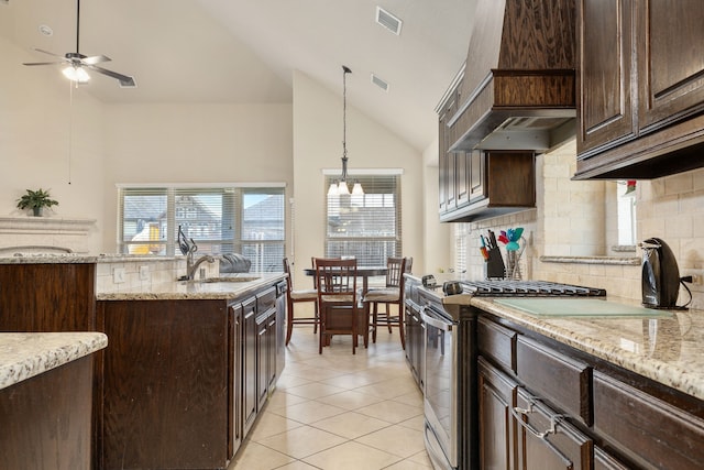 kitchen featuring hanging light fixtures, high vaulted ceiling, light tile patterned flooring, stainless steel range with gas stovetop, and sink