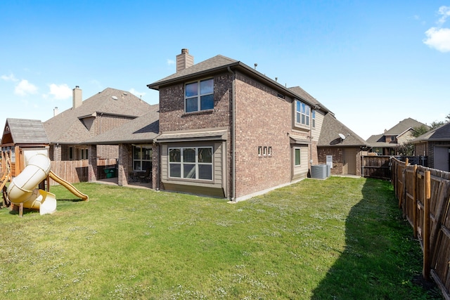 rear view of property featuring a lawn, a playground, and central AC unit