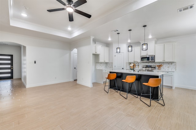 kitchen featuring white cabinetry, pendant lighting, stainless steel appliances, and an island with sink