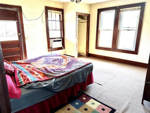 bedroom with cooling unit, multiple windows, and light colored carpet