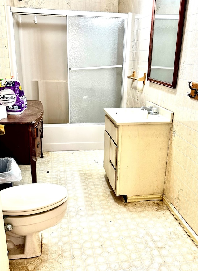 full bathroom with vanity, tile walls, enclosed tub / shower combo, and toilet