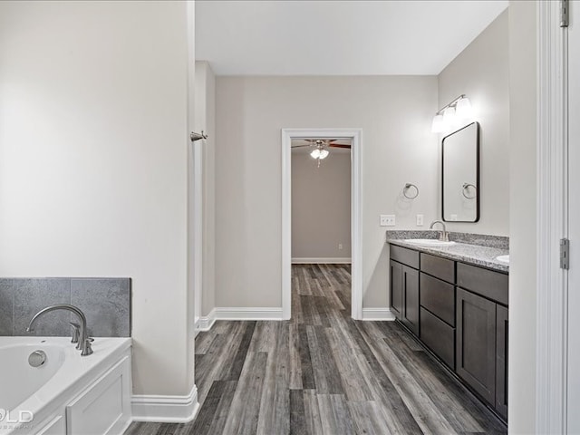 bathroom featuring vanity, a bathing tub, hardwood / wood-style floors, and ceiling fan