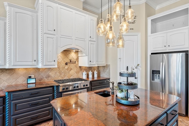 kitchen with white cabinets, appliances with stainless steel finishes, a center island with sink, and dark stone counters