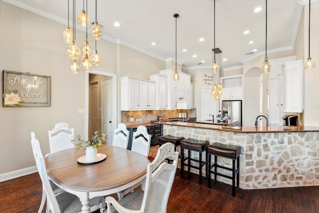 dining area with crown molding, dark hardwood / wood-style flooring, and sink