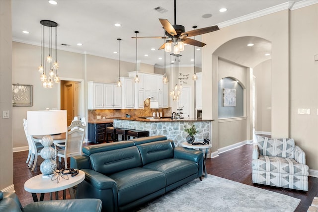 living room featuring ornamental molding, ceiling fan, dark wood-type flooring, and sink